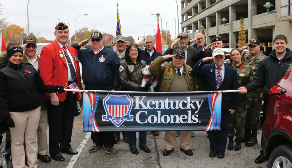 A group of Kentucky Colonels holding the Honorable Order banner at a parade