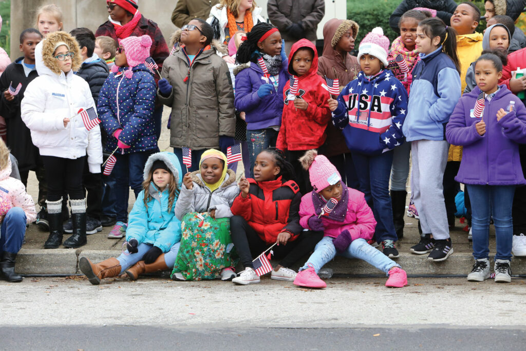 Kids at parade holding American flags.
